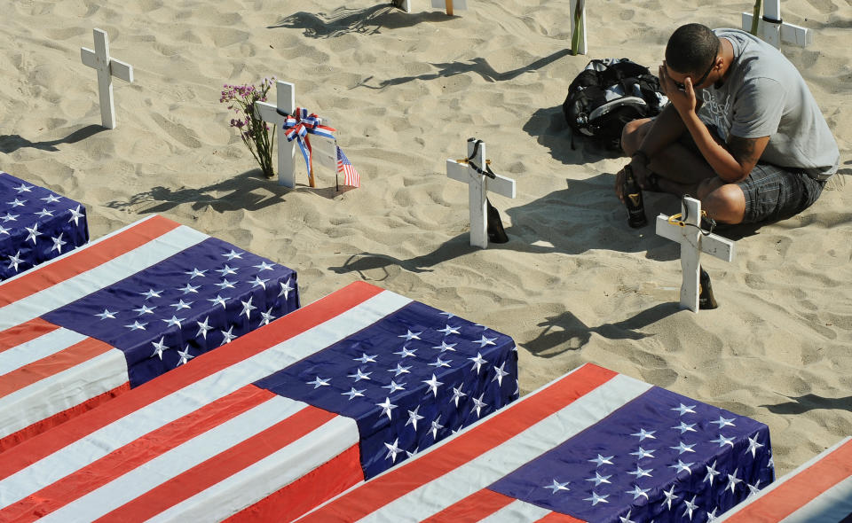 An Iraq War veteran sits and drinks a beer beside the symbolic graves of fallen friends, Sgt. Eric Snell and Pfc Michael Pittman, both from his former unit, the 1st Infantry Division, at the Arlington West Memorial on Memorial Day in Santa Monica, California, on May 30, 2011.