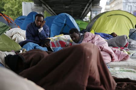 Migrants from Eritrea sit near tents as they live in a make-shift camp under a metro bridge in Paris, France, May 28, 2015. REUTERS/Benoit Tessier