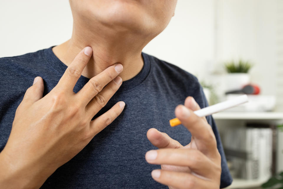 Neck of male smoker have a sore throat,painful and inflammation caused by smoking,man patient holding a cigarette has phlegm in his throat suffering from laryngeal cancer,throat cancer disease concept