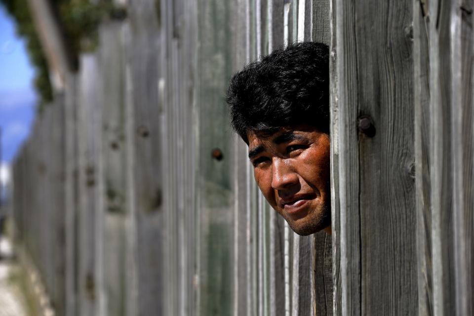 An Afghan immigrant looks through a wooden fence in a factory as he prepares to make a run towards the ferry terminal in the western Greek town of Patras (Getty)