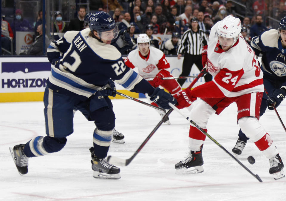 Columbus Blue Jackets defenseman Jake Bean, left, tries to pass the puck past Detroit Red Wings forward Pius Suter during the first period of an NHL hockey game in Columbus, Ohio, Monday, Nov. 15, 2021. (AP Photo/Paul Vernon)