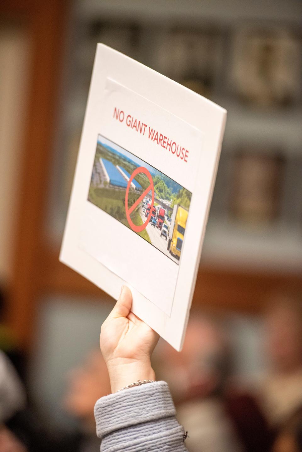 An attendee holds a sign opposing a warehouse proposed by Diamond Chip Realty on Demarest Road during a meeting of the Sparta Planning Board on Wednesday, April 6, 2022. 