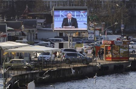 A screen, showing Russian President Vladimir Putin's annual end-of-year news conference, is on display on an embankment of the Black Sea port of Sevastopol, Crimea, December 17, 2015. REUTERS/Pavel Rebrov