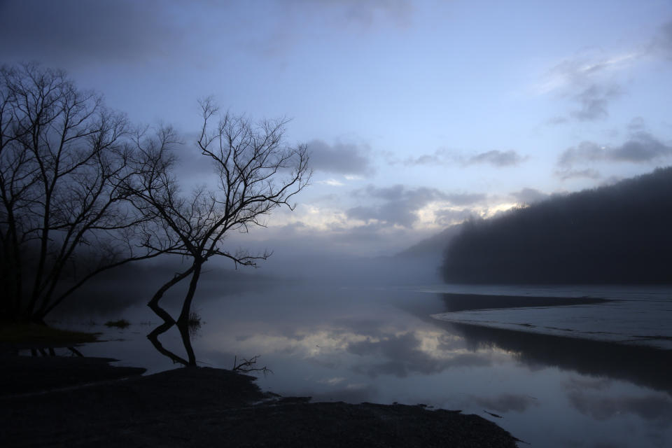 Clouds are reflected on a lake at dawn in Bluefield, W.Va, on Tuesday, Jan. 26, 2021. Members of three congregations in a small city in West Virginia’s ‘Trump Country’ face a reckoning over Christianity and the misuse of symbols of their faith in America’s divisive politics. (AP Photo/Jessie Wardarski)