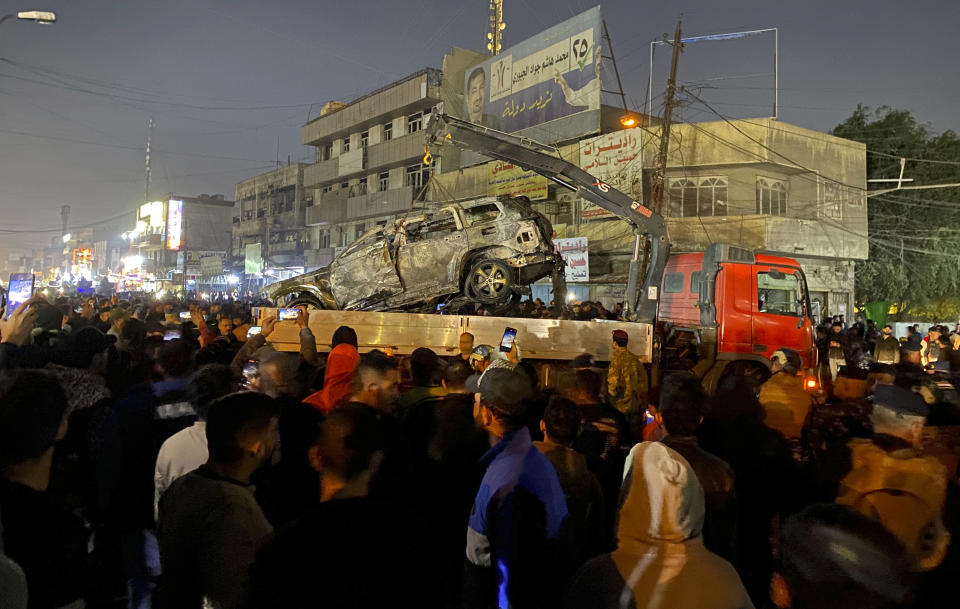 Iraqis gather at the site of a burned vehicle targeted by a U.S. drone strike in east Baghdad, Iraq, Wednesday, Feb. 7, 2024. (AP Photo/Hadi Mizban)