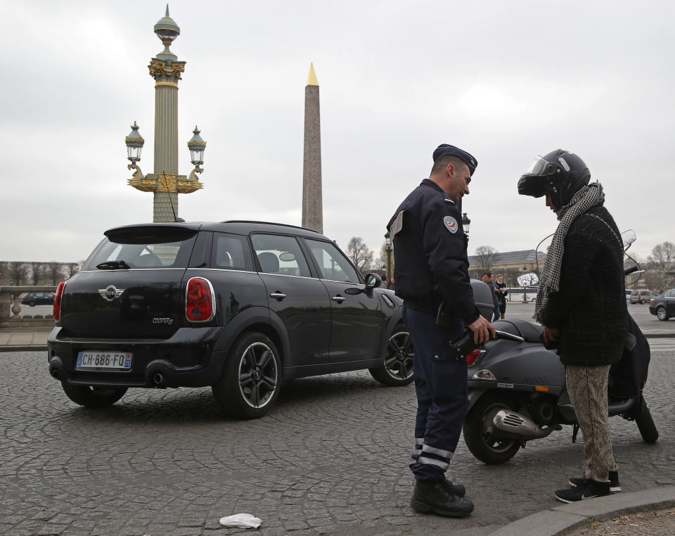 A police officer stops a scooter at Concorde square in Paris, Monday, March 17, 2014. Cars with even-numbered license plates are prohibited from driving in Paris and its suburbs Monday, following a government decision over the weekend. Paris is taking drastic measures to combat its worst air pollution in years, banning around half of the city's cars and trucks from its streets in an attempt to reduce the toxic smog that's shrouded the City of Light for more than a week. (AP Photo/Michel Euler)