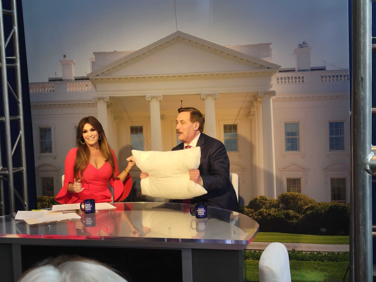 Mike Lindell holds up a MyPillow product as he is interviewed by Kimberly Guilfoyle at CPAC (John Bowden)