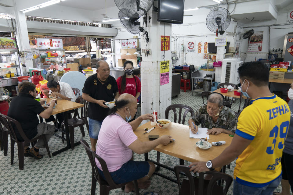 Customers have breakfast at a local restaurant in Kuala Lumpur, Malaysia, on Monday, May 4, 2020. Many business sectors reopened Monday in some parts of Malaysia since a partial virus lockdown began March 18. The easing of restrictions, days before the lockdown was due to end May 12, came as Prime Minister Muhyiddin Yassin's government sought to balance between curbing the virus and reviving the hard-hit economy.(AP Photo/Vincent Thian)