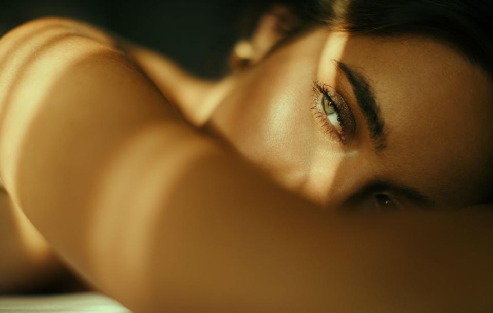 close up portrait of beautiful and sensual young woman lying on bed beautiful shadows and sunlight cover her face