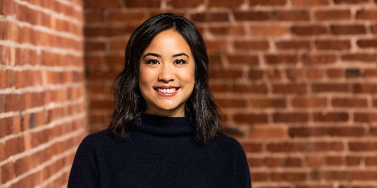 Susan Liu, a partner at Uncork Capital, smiles for a photo against a brick wall.