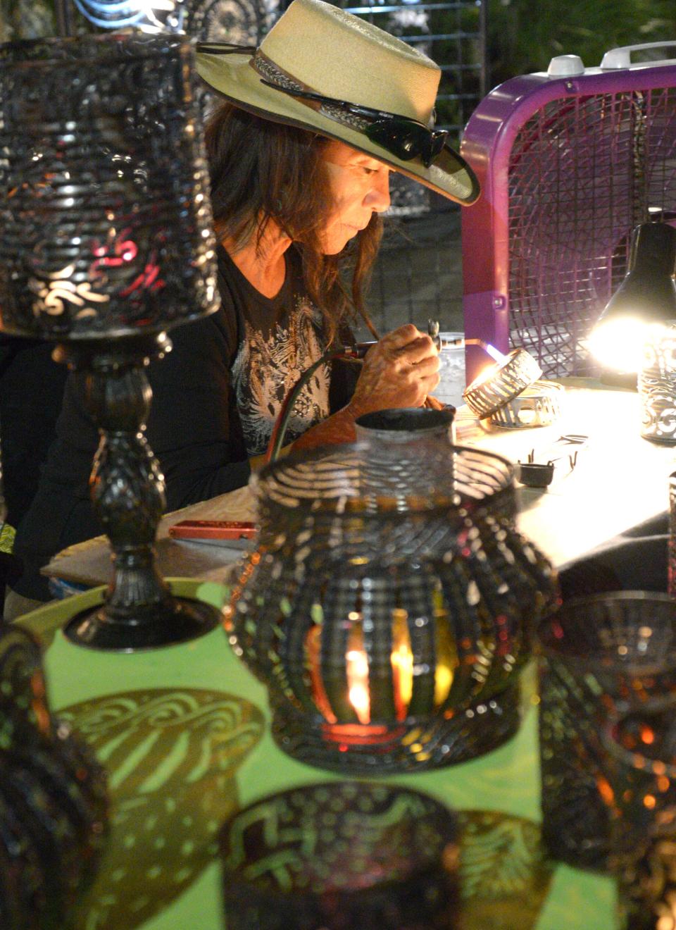 With a steady hand and concentration, Sue Durazo uses a small metal cutting torch on metal tin cans to create night lights, candle holders and other luminaries.