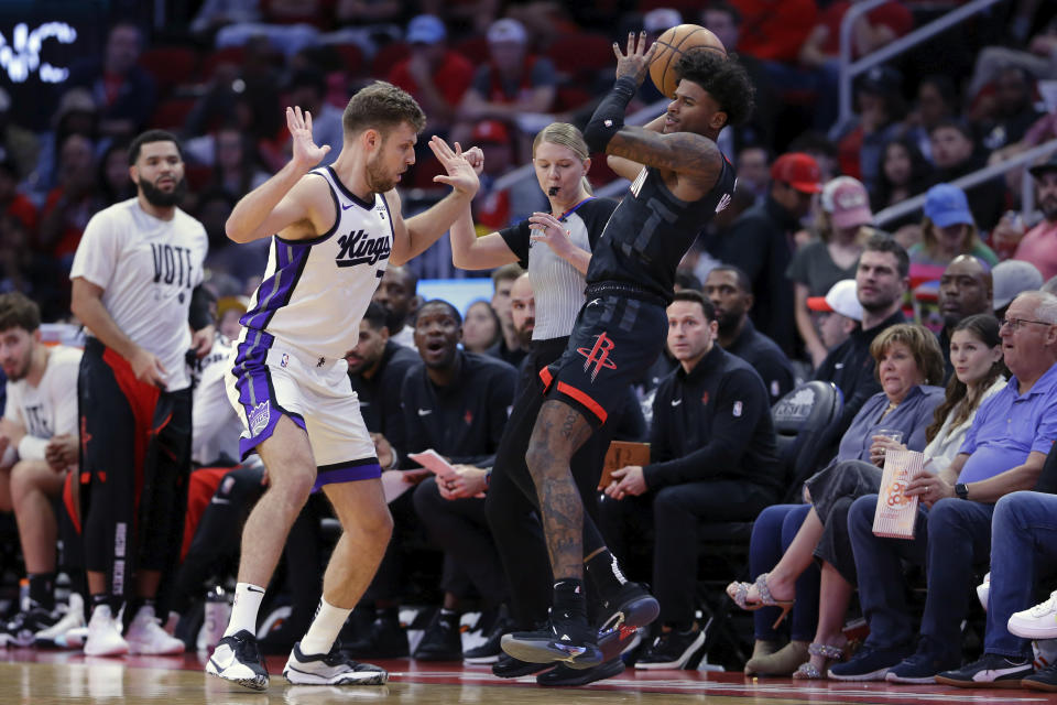 Houston Rockets guard Jalen Green, right, tries to stay in the court whiles passing the ball, as Sacramento Kings forward Sasha Vezenkov, left, avoids a foul during the first half of an NBA basketball game Saturday, Nov. 4, 2023, in Houston. (AP Photo/Michael Wyke)