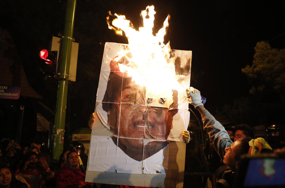 Anti-government protesters burn a picture President Evo Morales during a march demanding a second round presidential election, in La Paz, Bolivia, Saturday, Oct. 26, 2019. Bolivia's official vote tally was revealed Friday pointing to an outright win for incumbent Evo Morales in a disputed presidential election that has triggered protests and growing international pressure on the Andean nation to hold a runoff ballot. (AP Photo/Juan Karita)