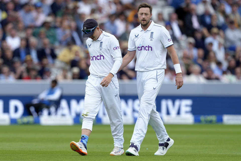 England's Ollie Robinson, right, pats teammate Ollie Pope after Pope hurt his shoulder during the third day of the second Ashes Test match between England and Australia, at Lord's cricket ground in London, Friday, June 30, 2023. (AP Photo/Kirsty Wigglesworth)