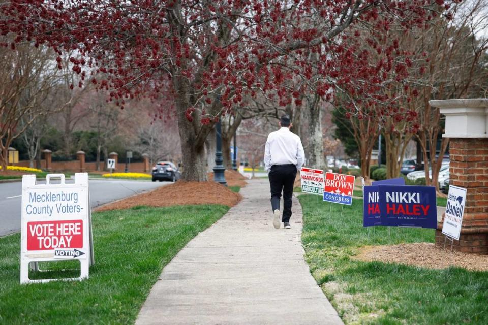 A sandwich board indicating a polling site accompanies campaign signs along the sidwalk outside South Park Library during early voting in Charlotte, NC on Tuesday, February 28, 2024.