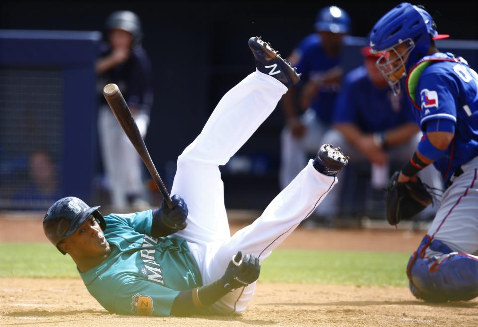 Seattle Mariners' Jean Segura, left, dives out of the way of an inside pitch as Texas Rangers' Robinson Chirinos, right, goes after the ball during the first inning of a spring training baseball game Saturday, March 25, 2017, in Peoria, Ariz. (AP Photo/Ross D. Franklin)