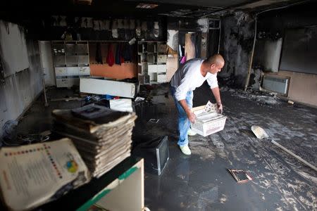 A worker cleans up in a torched classroom in an Arab-Jewish school in Jerusalem November 30, 2014. REUTERS/Ronen Zvulun