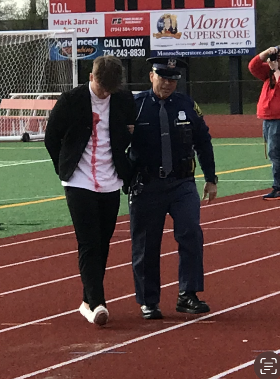 Kellen Roberts, who played the drunken driver, is led away by Trooper Don Stewart of the Michigan State Police during a mock crash and rescue put on Thursday morning at Monroe High School.