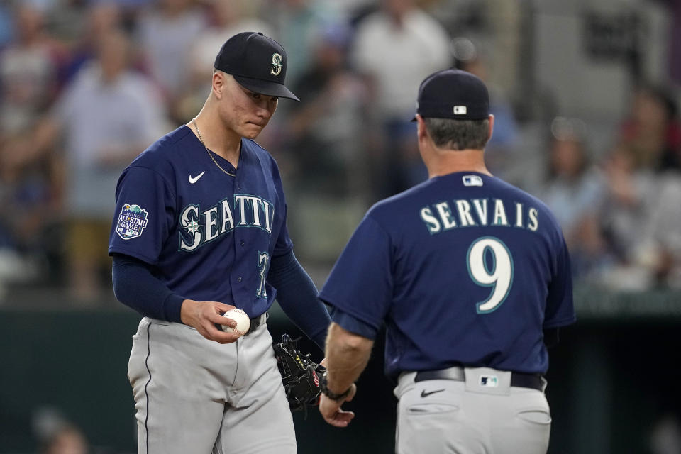 Seattle Mariners starting pitcher Bryan Woo, left, turns the ball over to manager Scott Servais (9) in the fourth inning of a baseball game against the Texas Rangers, Sunday, Sept. 24, 2023, in Arlington, Texas. (AP Photo/Tony Gutierrez)