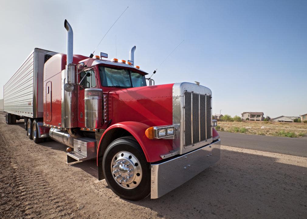 Red semitruck parked on the side of the road.