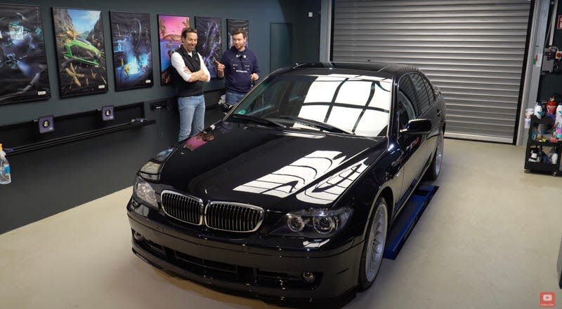 Two men in a garage stand behind a BMW Alpina B7 with extremely glossy paint.