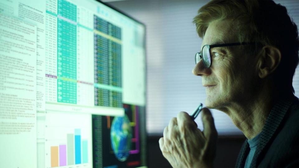 A person looking closely at a computer screen with stock information 