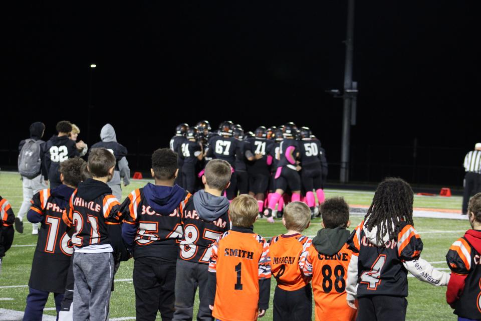 Youth football players look on as Gardner captains join Littleton captains and the referees for the coin ceremony prior to the game on October 13, 2023.