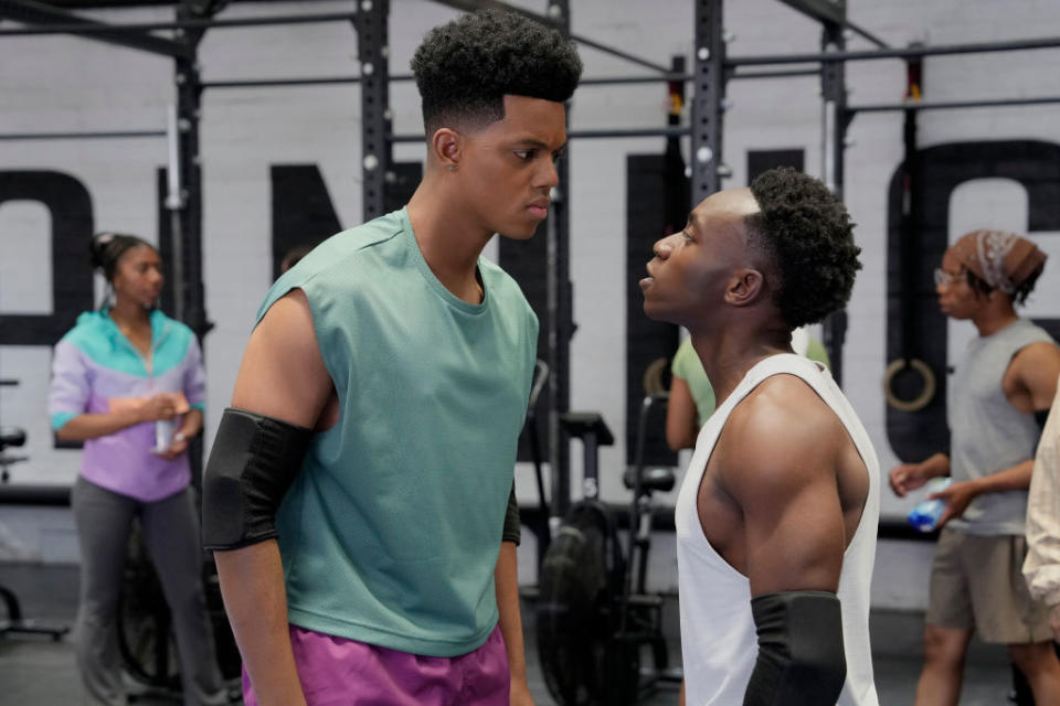 Jabari Banks and Olly Sholotan face each other in a gym scene "Bel Air." Jabari wears a sleeveless top with elbow pads and Olly wears a tank top