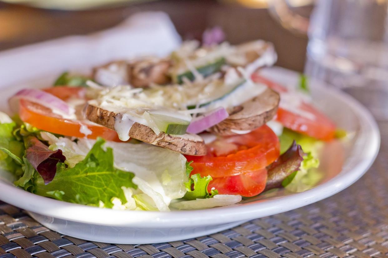 Vegetarian salad with ranch dressing with fresh mushrooms tomatoes cucumbers red onion and parmesan cheese