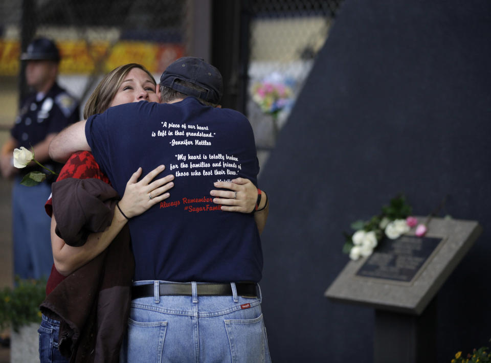 Lacey Grabek, of Noblesville, Ind., left, and Richard Lindsay of Tecumseh, Mich., who both attended last years Sugarland concert, hug in front of a plaque honoring the six killed when stage rigging collapsed at the Indiana State Fair in Indianapolis a year ago, Monday, Aug. 13, 2012. A moment of silence for the victims and injured was held at the fair at the time of the collapse. (AP Photo/Michael Conroy)