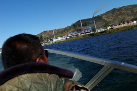 Man looks at a North Korean factory from a boat over the Yalu river separating North Korea's Sinuiju and China's Dandong in Liaoning province