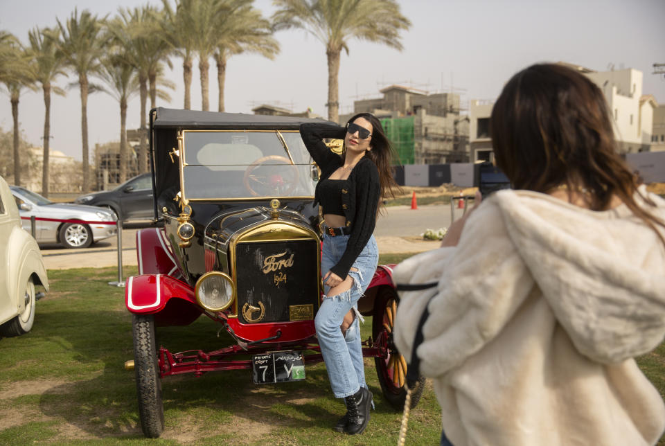 Classic cars enthusiast Carine Sherif poses in front of a 1924 Ford T owned by Egyptian collector Mohamed Wahdan during a classic car show in Cairo, Egypt, Saturday, March 19, 2022. The car once belonged to Egypt's King Farouk's and is a part of over 250 vintage, antique and classic cars Wahdan collected over the past 20 years. (AP Photo/Amr Nabil)