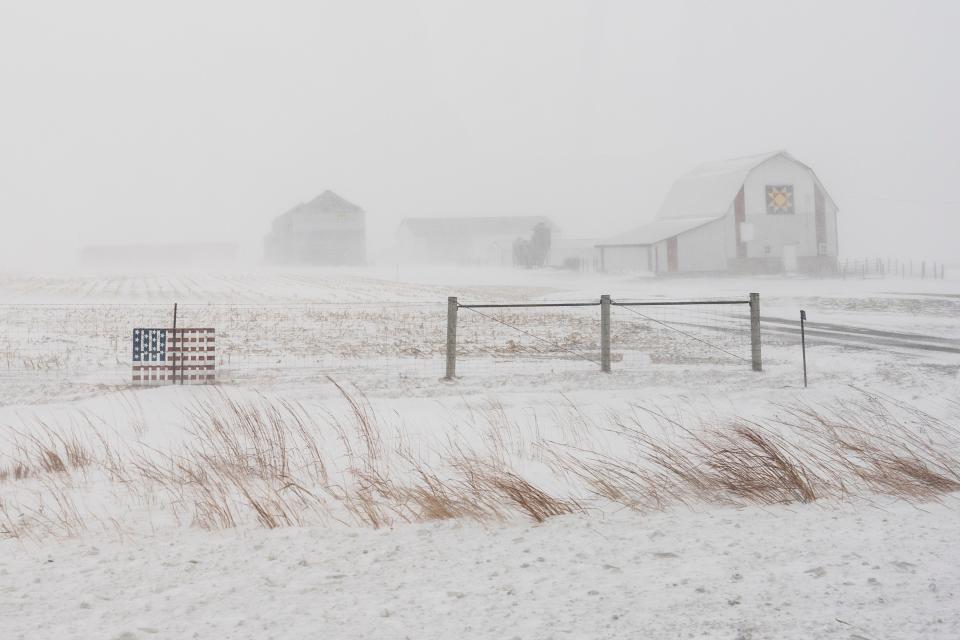 An American flag is seen fixed to a farm fence along US Highway 20 during a blizzard near Galva, Iowa, Saturday, Jan. 13, 2024. (AP Photo/Carolyn Kaster) ORG XMIT: IACK101