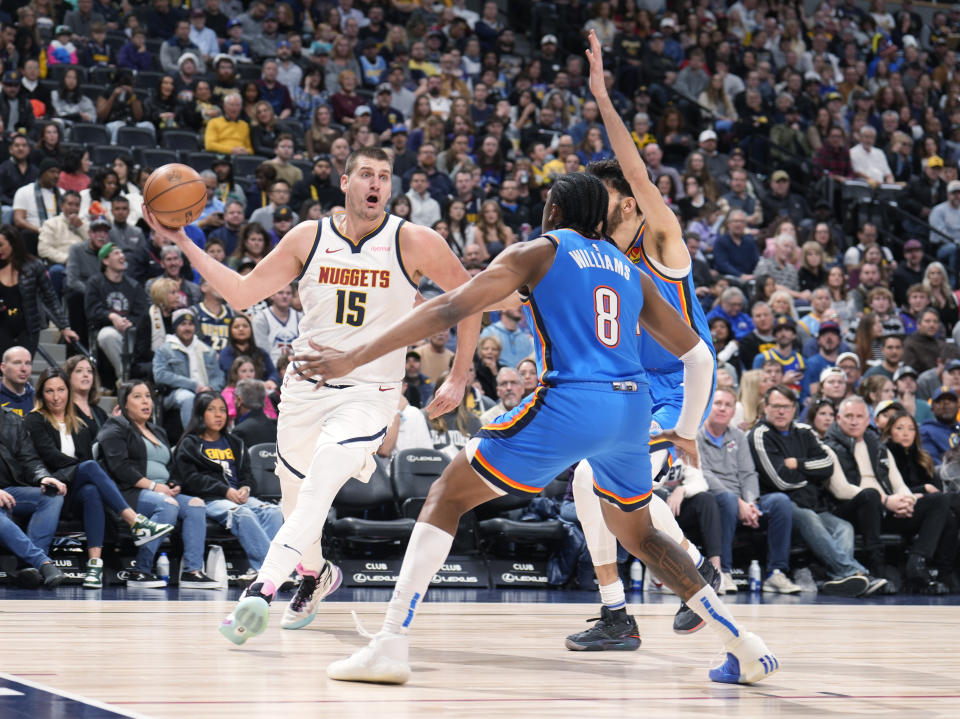 Denver Nuggets center Nikola Jokic, left, looks to pass the ball as Oklahoma City Thunder forwards Jalen Williams, front right, and Chet Holmgren, back right, defend in the first half of an NBA basketball game Friday, Dec. 29, 2023, in Denver. (AP Photo/David Zalubowski)