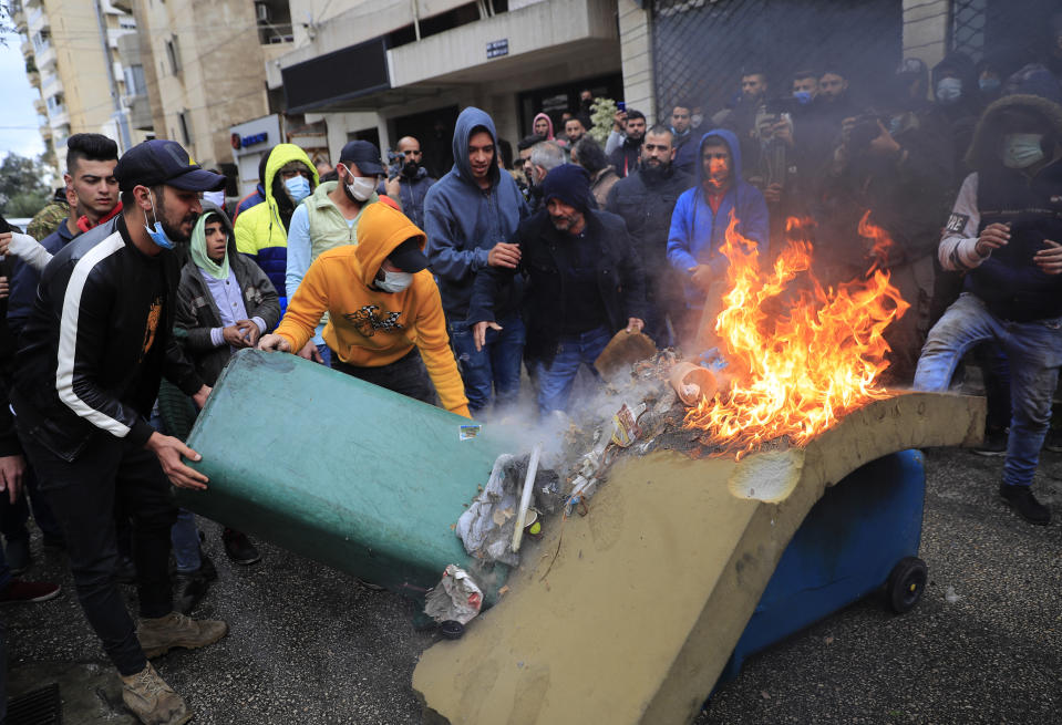 Protesters set fire to garbage containers in front the house of a Lebanese lawmaker, during a protest against deteriorating living conditions and strict coronavirus lockdown measures, in Tripoli, north Lebanon, Thursday, Jan. 28, 2021. Violent confrontations overnight between protesters and security forces in northern Lebanon left a 30-year-old man dead and more than 220 people injured, the state news agency said Thursday. (AP Photo/Hussein Malla)