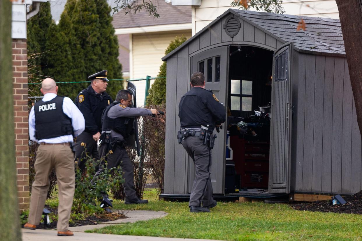 Hanover Borough police officers clear a shed with guns drawn as they work to secure the scene where three people died in a stabbing incident at 950 East Walnut Street in Hanover.