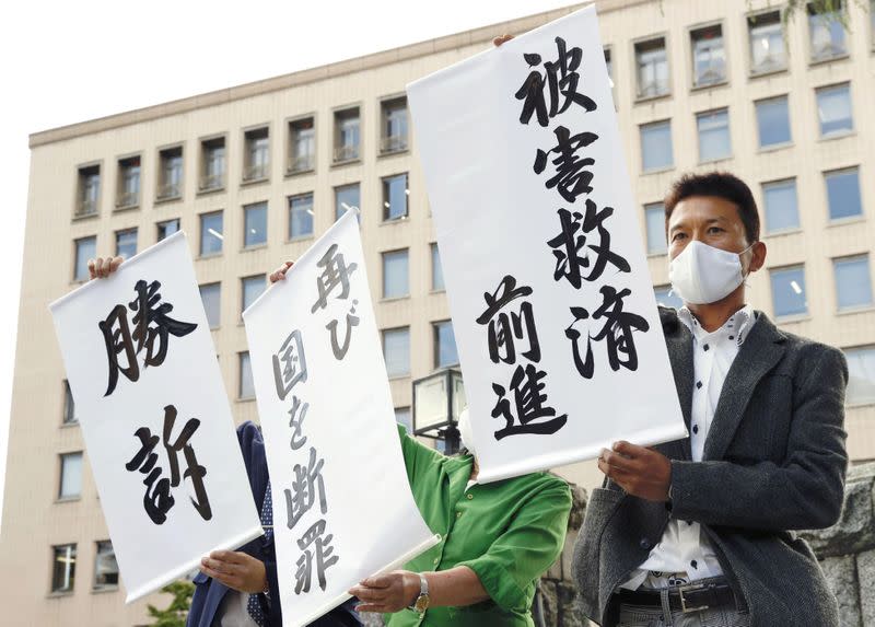 Members of a group of plaintiffs show off banners reading 'Winning the case' and other messages in front of the Sendai High Court after the court's ruling in Sendai