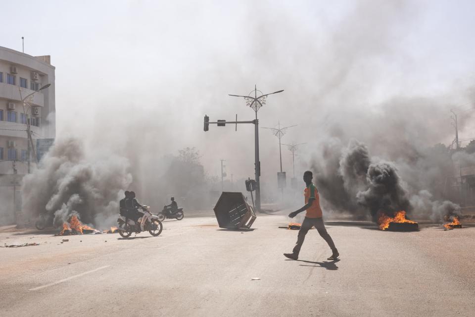 Un homme traverse des barricades en feu dans les avenues centrales de Ouagadougou le 23 janvier 2022. Des soldats se sont mutinés dimanche dans plusieurs casernes du Burkina Faso pour exiger le départ des chefs d'armée et des 