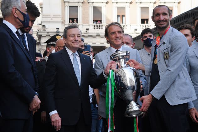 Italy's Prime Minister, Mario Draghi (L) holds with Italy's coach Roberto Mancini (C) and Italy's defender Giorgio Chiellini (R) the UEFA EURO 2020 trophy as players of Italy's national football team arrive to attend a ceremony at the prime minister's office Palazzo Chigi in Rome on July 12, 2021, a day after Italy won the UEFA EURO 2020 final football match between Italy and England. (Photo by Tiziana FABI / AFP) (Photo by TIZIANA FABI/AFP via Getty Images) (Photo: TIZIANA FABI via Getty Images)