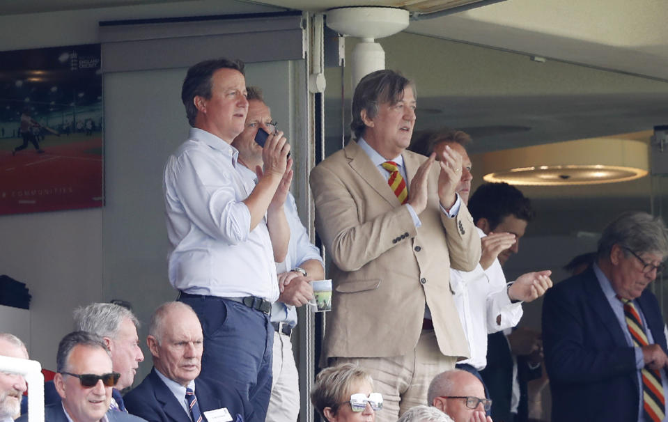 Former British Prime Minister David Cameron, left with TV personality and writer Stephen Fry watch the Cricket World Cup match between England and Australia at Lord's cricket ground in London, Tuesday, June 25, 2019. (AP Photo/Alastair Grant)