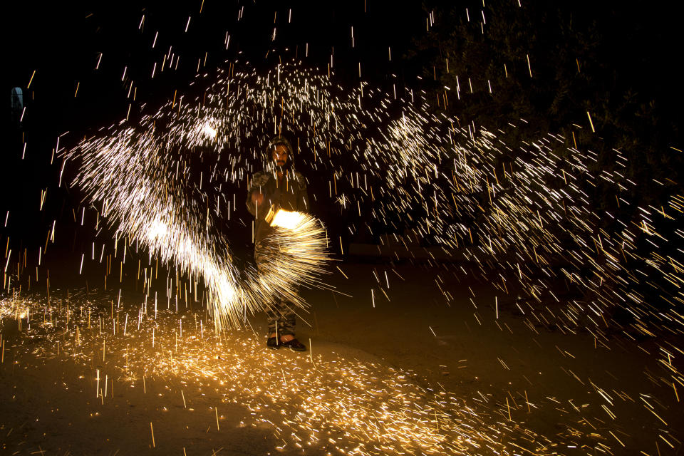 A Palestinian plays with fireworks as he celebrates the start of the Muslim holy month of Ramadan in the West Bank city of Nablus, Thursday, April. 23, 2020.