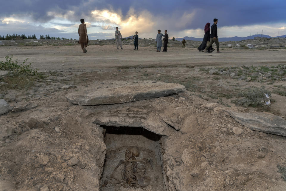 Afghan boys play next to a destroyed grave at a cemetery in Kabul, Afghanistan, Thursday, May 5, 2022. There are cemeteries all over Afghanistan's capital, Kabul, many of them filled with the dead from the country's decades of war. They are incorporated casually into Afghans' lives. They provide open spaces where children play football or cricket or fly kites, where adults hang out, smoking, talking and joking, since there are few public parks. (AP Photo/Ebrahim Noroozi)