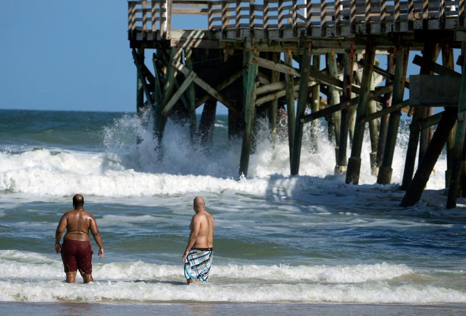 A pair of beachgoers watch as waves start to crash under the Daytona Pier in Daytona Beach, where the initial effects of Subtropical Storm Nicole were evident long before its expected approach on Wednesday. Volusia and Flagler county officials urged residents to prepare now.