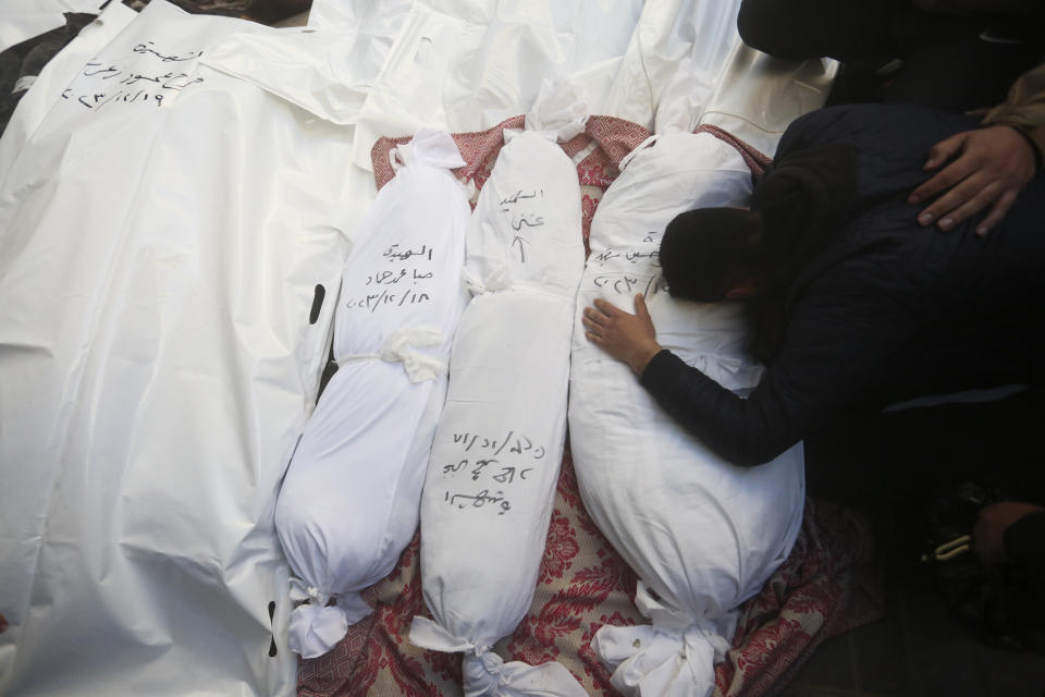 Palestinians mourn relatives killed in the Israeli bombardment of the Gaza Strip outside a morgue in Rafah, Tuesday, Dec. 19, 2023. (AP Photo/Hatem Ali)