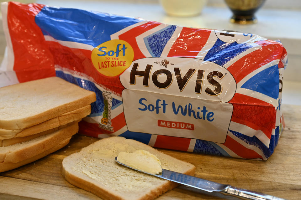 A loaf of Hovis Soft White bread with some slices out and one buttered, next to a knife