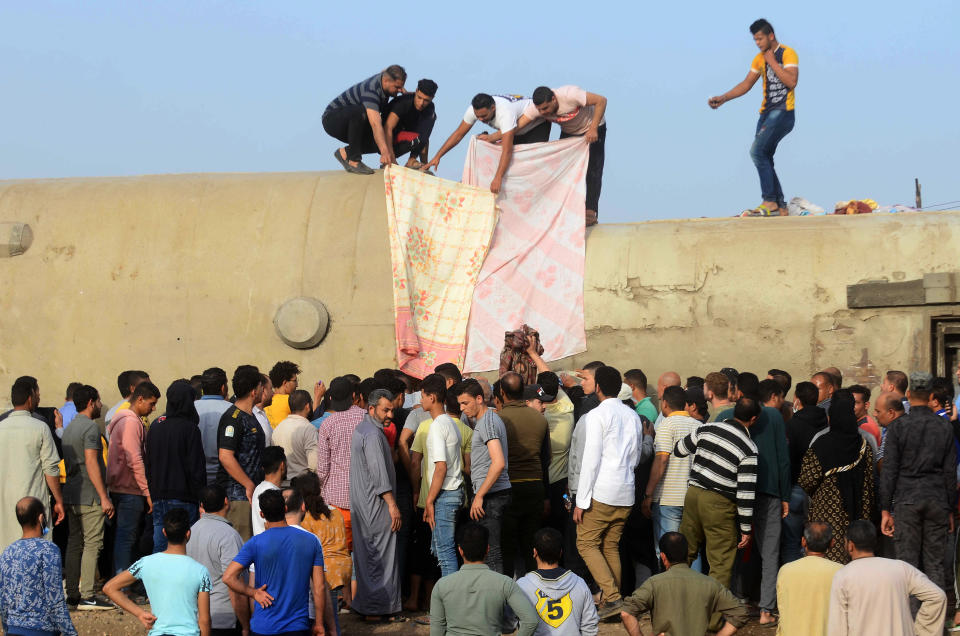 People gather at the site where a passenger train derailed injuring at least 100 people, near Banha, Qalyubia province, Egypt, Sunday, April 18, 2021. At least eight train wagons ran off the railway, the provincial governor's office said in a statement. (AP Photo/Tarek Wagih)