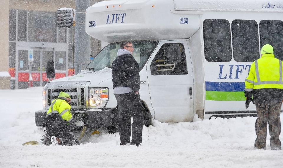 An Erie Metropolitan Transit Authority crew tries to dig out a LIFT van stuck in snow on Monday at the intersection of West 12th Street and Pittsburgh Avenue in Erie. A heavy EMTA wrecker was seen traveling in their direction shortly after.