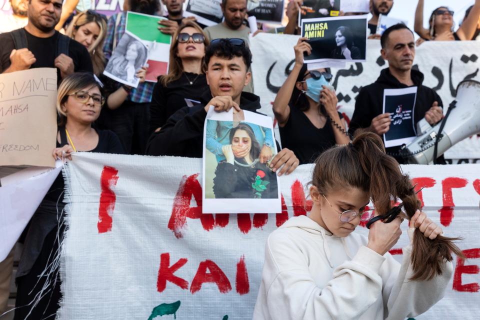 A woman cuts her hair during a protest against the death of Iranian Mahsa Amini, at central Syntagma square, in Athens, Greece, Saturday, Sept. 24, 2022.