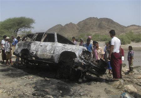 People gather at the site of a drone strike on the road between the Yafe and Radfan districts of the southern Yemeni province of Lahj in this August 11, 2013 file photo. REUTERS/Stringer/Files