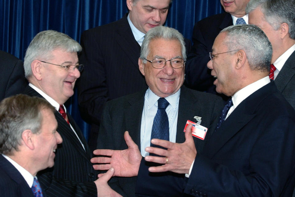 FILE - In this Dec. 9, 2004 file photo, U.S. Secretary of State Colin Powell, front right, reaches out to German Foreign Minister Joschka Fischer, second left, as Greek Foreign Minister Petros Molyviatis, center, looks on during a group photo of NATO foreign ministers at NATO headquarters in Brussels. Powell, former Joint Chiefs chairman and secretary of state, has died from COVID-19 complications. In an announcement on social media Monday, the family said Powell had been fully vaccinated. He was 84. (AP Photo/Virginia Mayo)